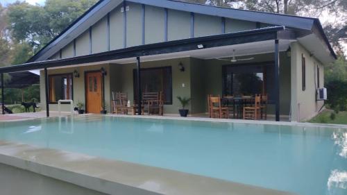 uma casa com piscina em frente a uma casa em Las Marukas em San Antonio de Areco