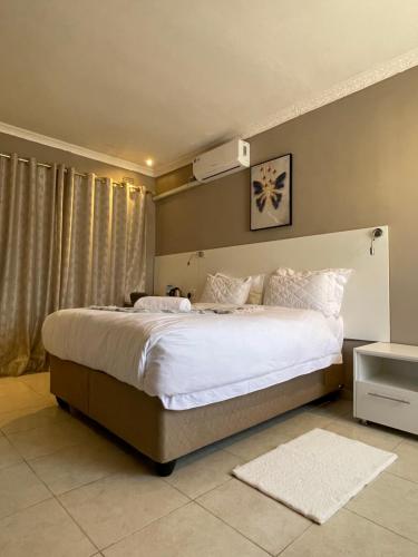 a bedroom with a large bed with white sheets at LEGENDS EXECUTIVE LODGE in Choma