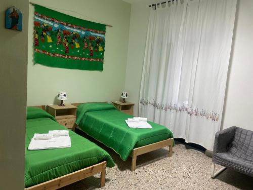 een kamer met 2 groene bedden en een vlag bij Beteyà Hostel Don Bosco in Catania