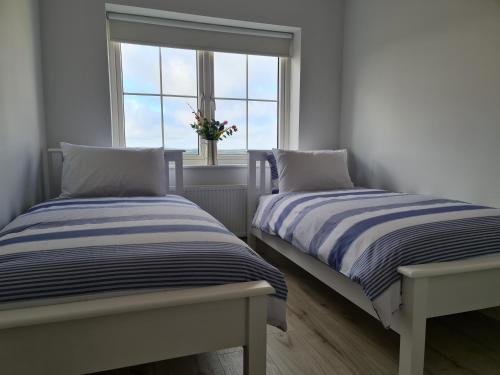 two beds in a room with a window at Abbeyfort Kinsale in Kinsale