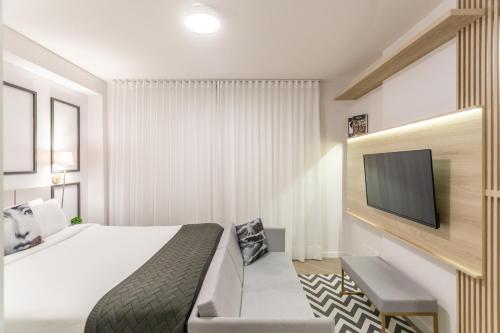 a hotel room with a bed and a flat screen tv at Charlie Porto Alegre Moinhos in Porto Alegre