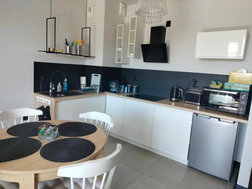 a kitchen with a wooden table and white cabinets at Apartament KUBIKS SADY in Malbork