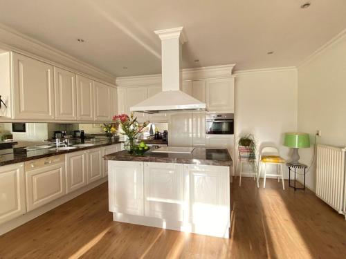 a kitchen with white cabinets and a large island at Amstel BeachHouse Egmond aan Zee, 50m from the beach! in Egmond aan Zee