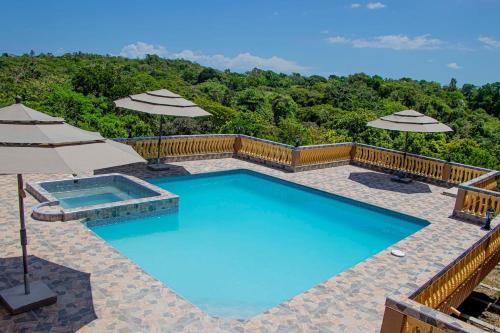 a large swimming pool with umbrellas on a patio at Blue Berry Hill Villa in Discovery Bay