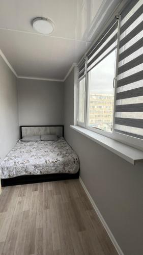 1 dormitorio con 1 cama en una habitación con ventana en Квартира 6-35, en Aktau