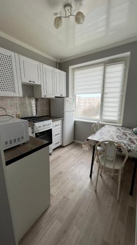 cocina con armarios blancos, mesa, mesa y sillas en Квартира 6-35 en Aktau