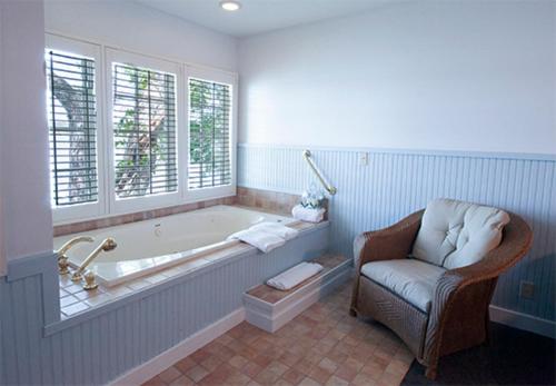 baño con bañera, silla y ventana en The Sand Hill Inn en Lake Geneva