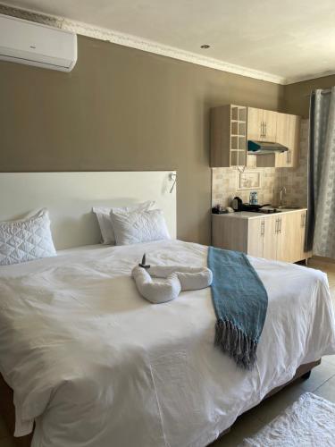 a large white bed with a stuffed animal on it at LEGENDS EXECUTIVE LODGE in Choma