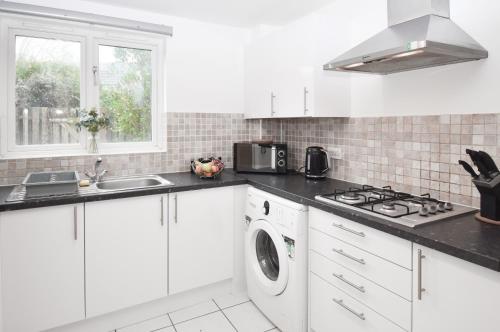 a white kitchen with a sink and a washing machine at Milton Keynes 5BR Contractor house, families/ groups welcome. in Broughton