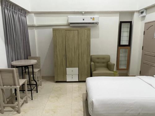 a bedroom with a bed and a chair and a table at Mall Suites Hotel in Bangkok