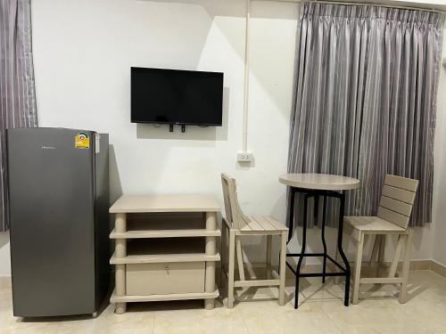 a room with a television and a table and chairs at Mall Suites Hotel in Bangkok