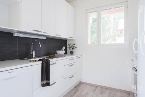 a white kitchen with a sink and a window at 100m2 moderni paritalo omalla pihalla Helsingissa in Helsinki