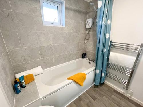 uma casa de banho com uma banheira e uma janela em 2 Bedroom Flat - Free Parking em Shenley Church End