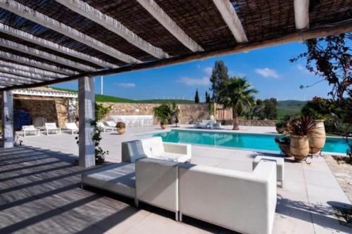 um pátio com mobiliário branco e uma piscina em Cortijo Almarchal em El Almarchal