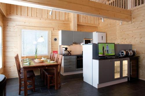 a kitchen with a table and a white refrigerator at Villa Kilpikonna in Mikkeli