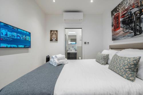 een slaapkamer met een groot wit bed en een televisie bij Luxurious Mews House Next to Hyde Park in Londen