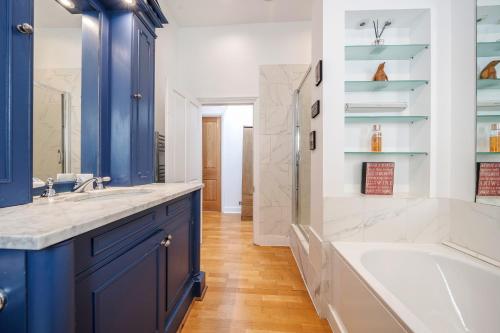 a bathroom with blue cabinets and a tub and a sink at Luxurious Mews House Next to Hyde Park in London