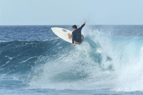 a man riding a wave on a surfboard in the ocean at Finimas Residence in Thimarafushi