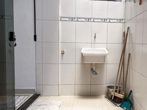 サルバドールにあるApto aconchegante de frente para praiaの白いタイル張りのバスルーム(シンク、シャワー付)