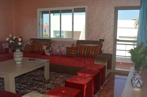 a living room with a red couch and a table at Oualidia29 in Oualidia