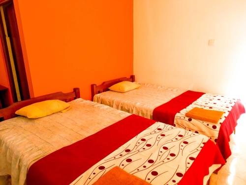 two beds in a room with orange walls at Awinco Haputale in Haputale