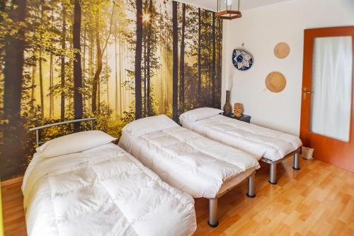 three beds in a room with a mural of trees at Attico con Vista in Turin