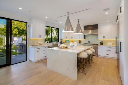 a kitchen with white cabinets and a large island with bar stools at Curson Modern in Los Angeles