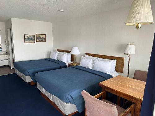 a hotel room with two beds and a table at Bayside Inn in Saint Ignace