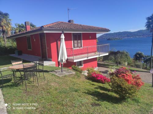 a red house with a table and an umbrella at Villetta Primavera in Verbania