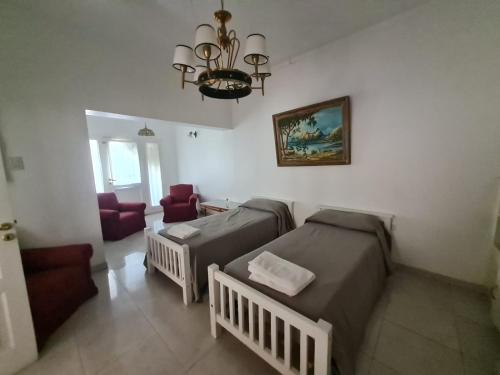 a bedroom with two beds and a chandelier at MENDOZA TURiSTA - CASA EN SAN MARTÍN, MENDOZA "ANTONIO's HOUSE" in San Martín