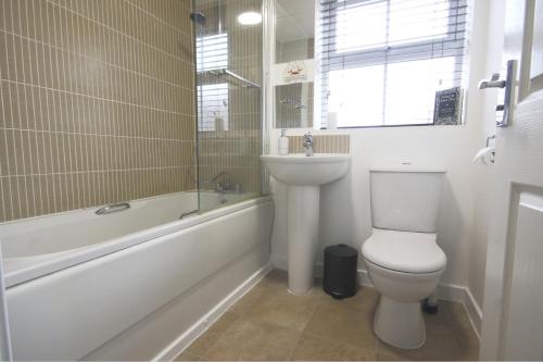 4ft Double bed with Parking & Wi-fi in Modern Townhouse in Long Eaton في لونغ إيتون: حمام مع مرحاض وحوض استحمام ومغسلة