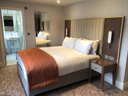 a hotel room with a large bed and a bathroom at voco The Clifton Folkestone by IHG in Folkestone