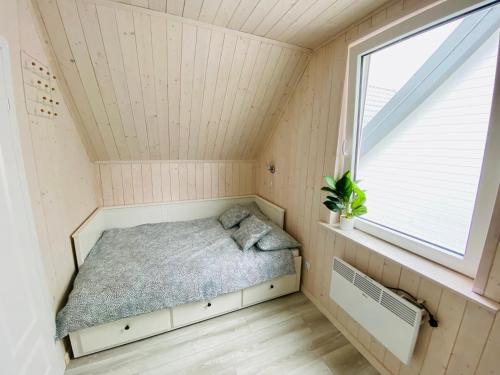 Una cama en una habitación pequeña con ventana. en Łapacz snów, en Władysławowo