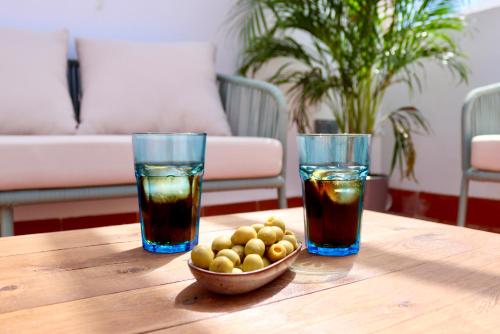 two drinks and a bowl of olives on a wooden table at La Plaza Hostal in Peñíscola