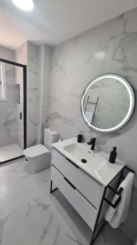 a white bathroom with a sink and a mirror at Albolafia junto Puente Romano in Córdoba