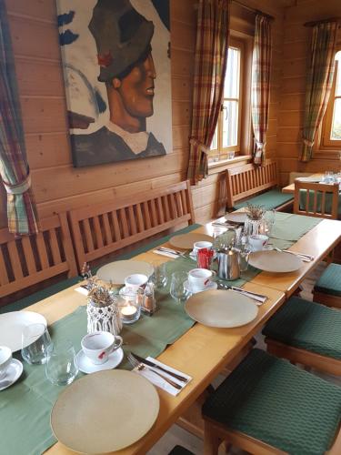 a long wooden table with plates and a painting on the wall at Weingut Reiterer in Kitzeck im Sausal