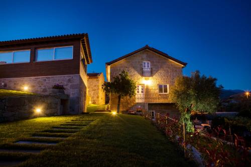 a house with lights on the side of it at night at Mãe - Casas de Selim in Arcos de Valdevez