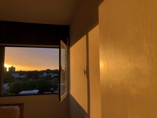 a room with a window with a view of the sunset at Cómodo apartamento en Colonia, cerca de todo in Colonia del Sacramento