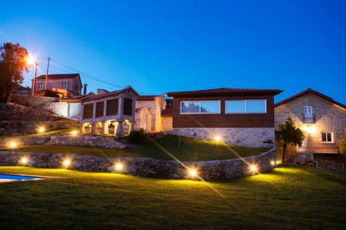 a house with lights in a yard at night at Eira - Casas de Selim in Arcos de Valdevez