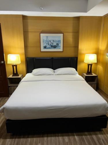 a bedroom with a large white bed with two lamps at Mall Suites Hotel in Bangkok