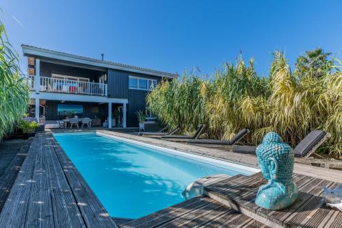 - une piscine avec une statue à côté d'une maison dans l'établissement Villa Perle du Bassin Vue Mer - Arcachon-La Hume, à Gujan-Mestras