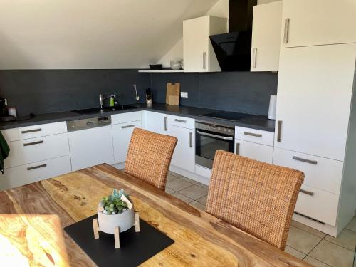 a kitchen with white cabinets and a table and chairs at FeWo Weitblick in ruhiger und gemütlicher Lage in Oberteuringen