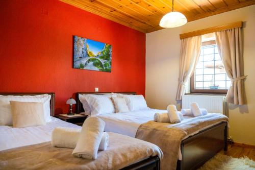 two beds in a room with red walls at Zagori Home in Monodendri