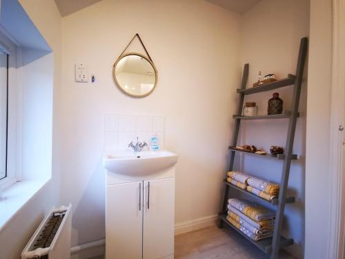 baño con lavabo y espejo en la pared en Rose Cottage en Conwy