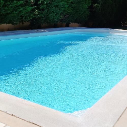 uma grande piscina azul com árvores ao fundo em Celestial Azure Villa, your Athenian Country House Retreat em Markopoulo Mesogaias