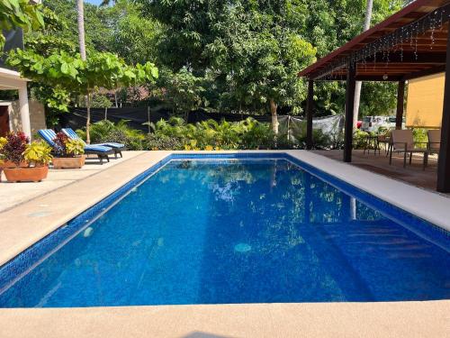 a blue swimming pool with a gazebo at Natura Hotel & Villas in Zihuatanejo