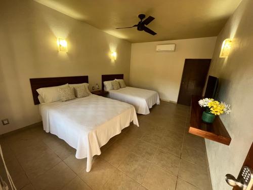 a bedroom with two beds and a ceiling fan at Natura Hotel & Villas in Zihuatanejo