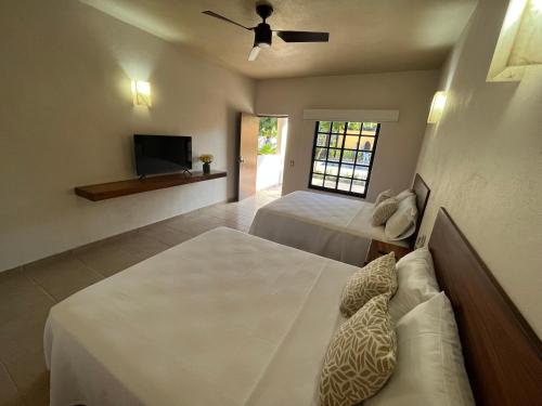 a bedroom with two beds and a flat screen tv at Natura Hotel & Villas in Zihuatanejo