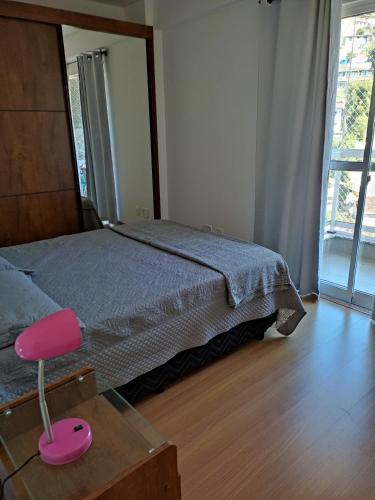 sypialnia z łóżkiem i różowym krzesłem w obiekcie Apartamento confortavel Centro de Teresopolis. NOVO w mieście Teresópolis
