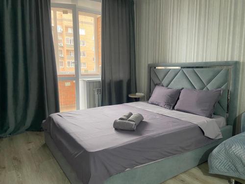 1 dormitorio con 1 cama con 2 toallas en Комфортабельные - уютные апартаменты в Костанай мкр Береке1, en Kostanái